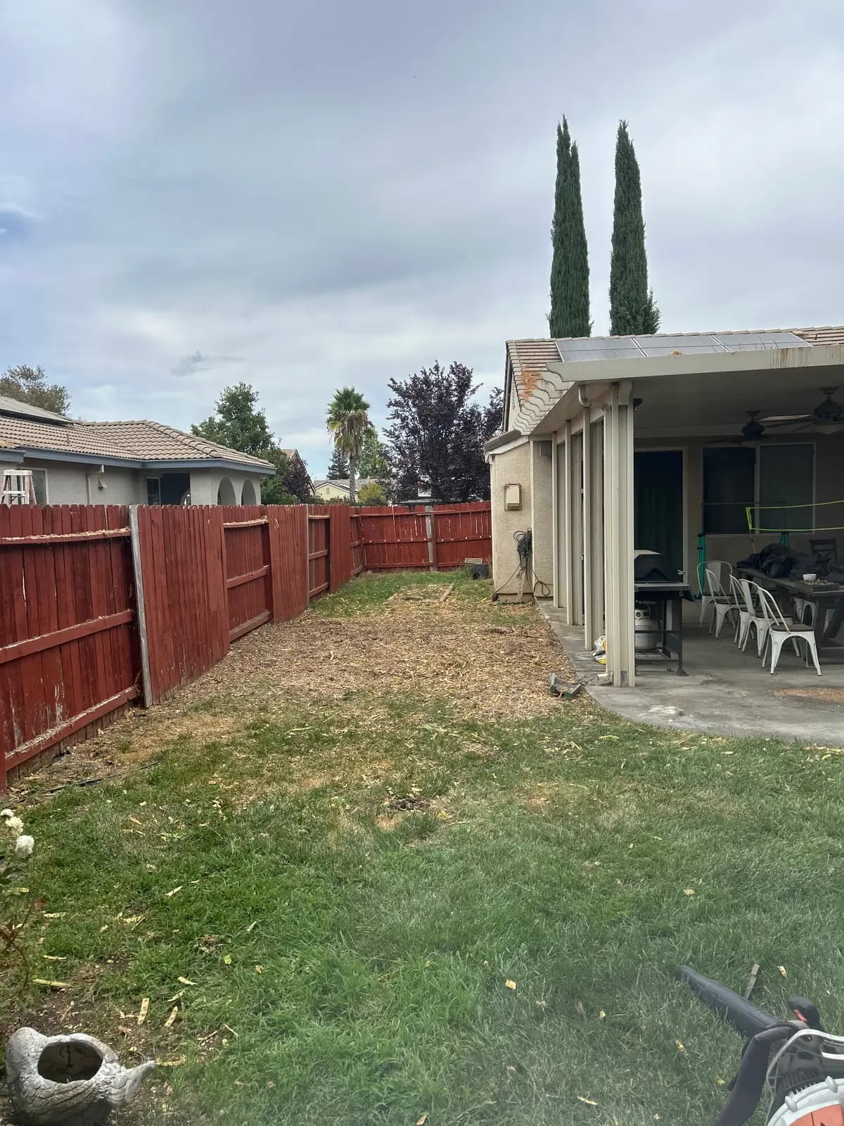 After: the same back yard cleared, with chips raked out and the patio open